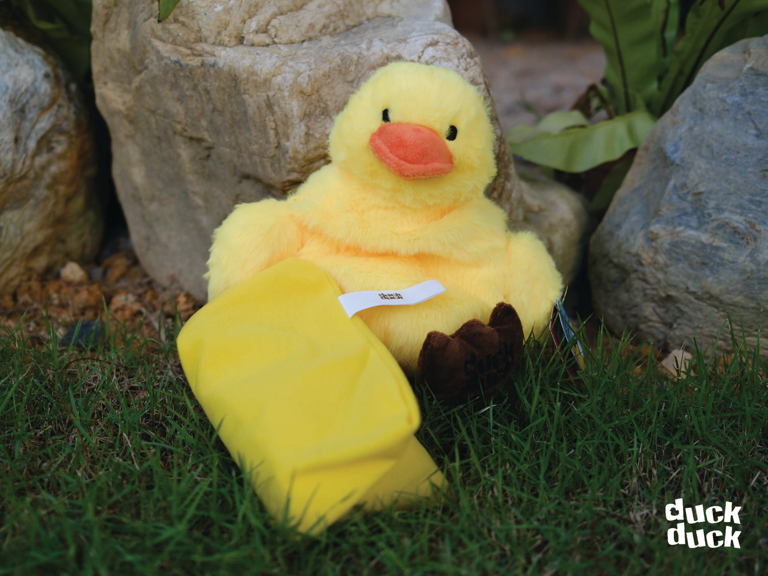 A plush yellow duck with a orange beak and brown feet, featuring a microwavable seed warmer insert.